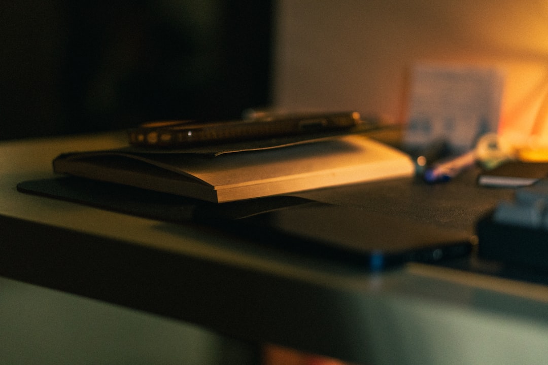 A desk with a notebook, pen, and scattered items
